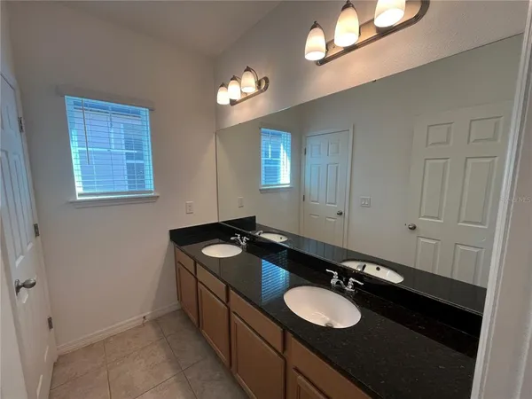 a bathroom with a granite countertop sink a light fixture and a mirror