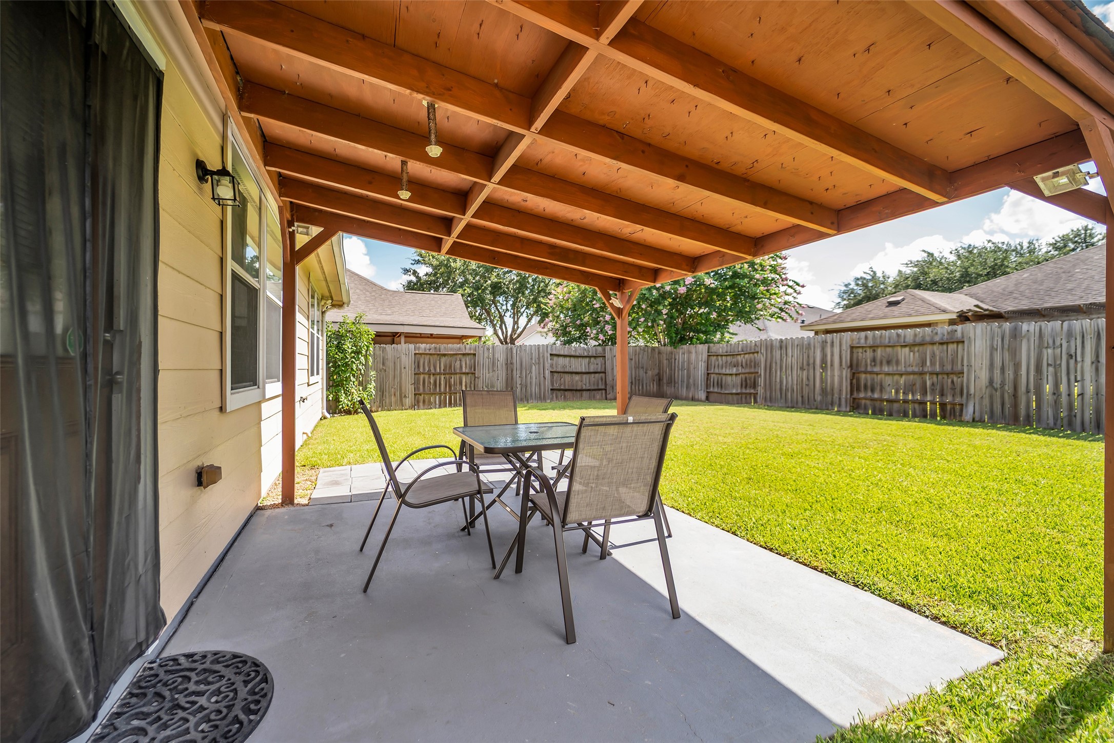 5406 Quarry Ridge Road Richmond, TX 77407 - Photo 35 of 36 Covered outdoor patio overlooking the fully fenced backyard, creating a comfortable space for outdoor dining, morning coffee, weekend gatherings, or relaxing in the shade. The spacious lawn extends beyond the patio, offering plenty of room for recreation, pets, gardening, or future outdoor enhancements.