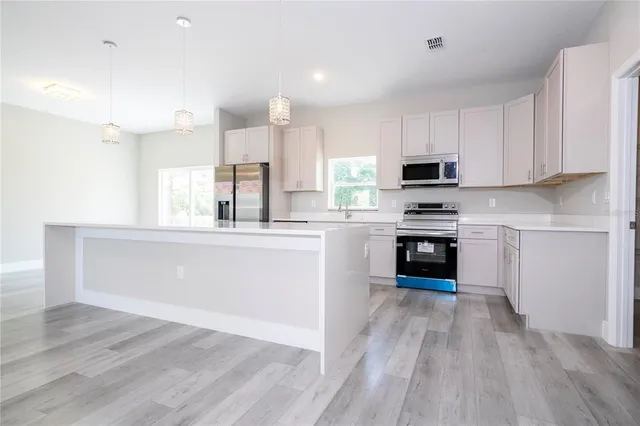a kitchen with stainless steel appliances kitchen island granite countertop a stove a sink and white cabinets
