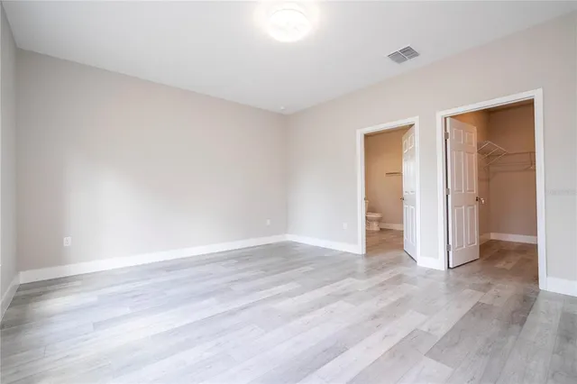 a view of an empty room with wooden floor and closet