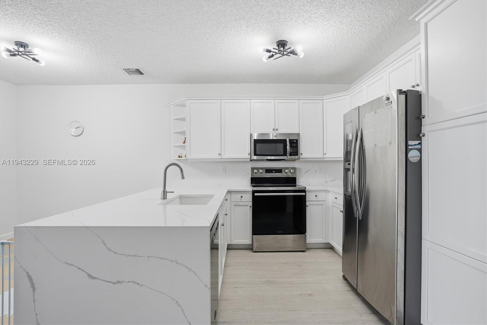 16367 Southwest 48th Street Miramar, FL 33027 - Photo 9 of 41 a kitchen with stainless steel appliances a refrigerator sink and white cabinets