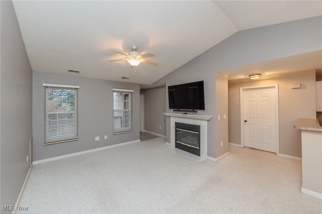 28360 Center Ridge Road, Unit 2210 Westlake, OH 44145 - Photo 7 of 45 Unfurnished living room featuring ceiling fan, light carpet, lofted ceiling, and a tile fireplace