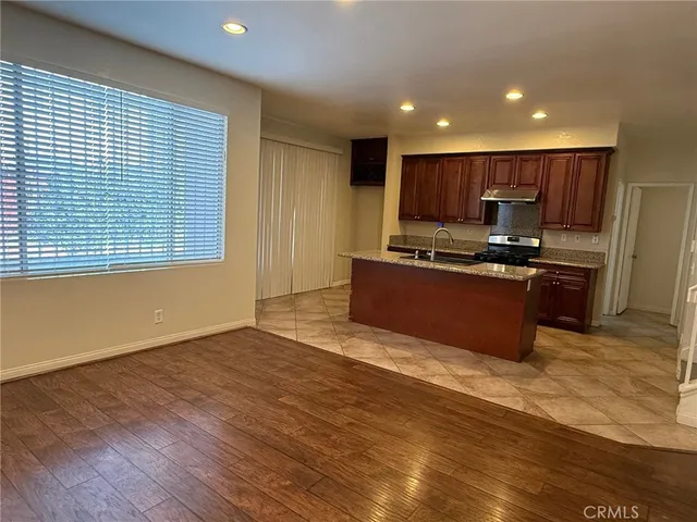 a open kitchen with kitchen island a sink wooden floor and a refrigerator