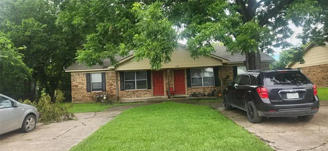a front view of a house with a garden and trees