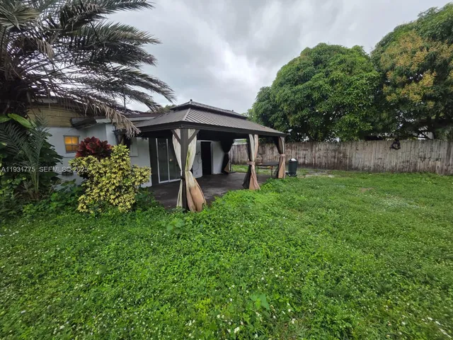 a view of a backyard with plants and large tree