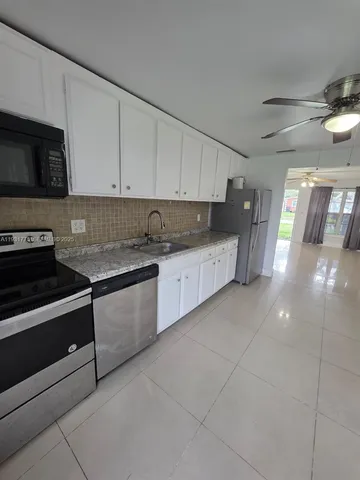a kitchen with granite countertop a stove and white cabinets
