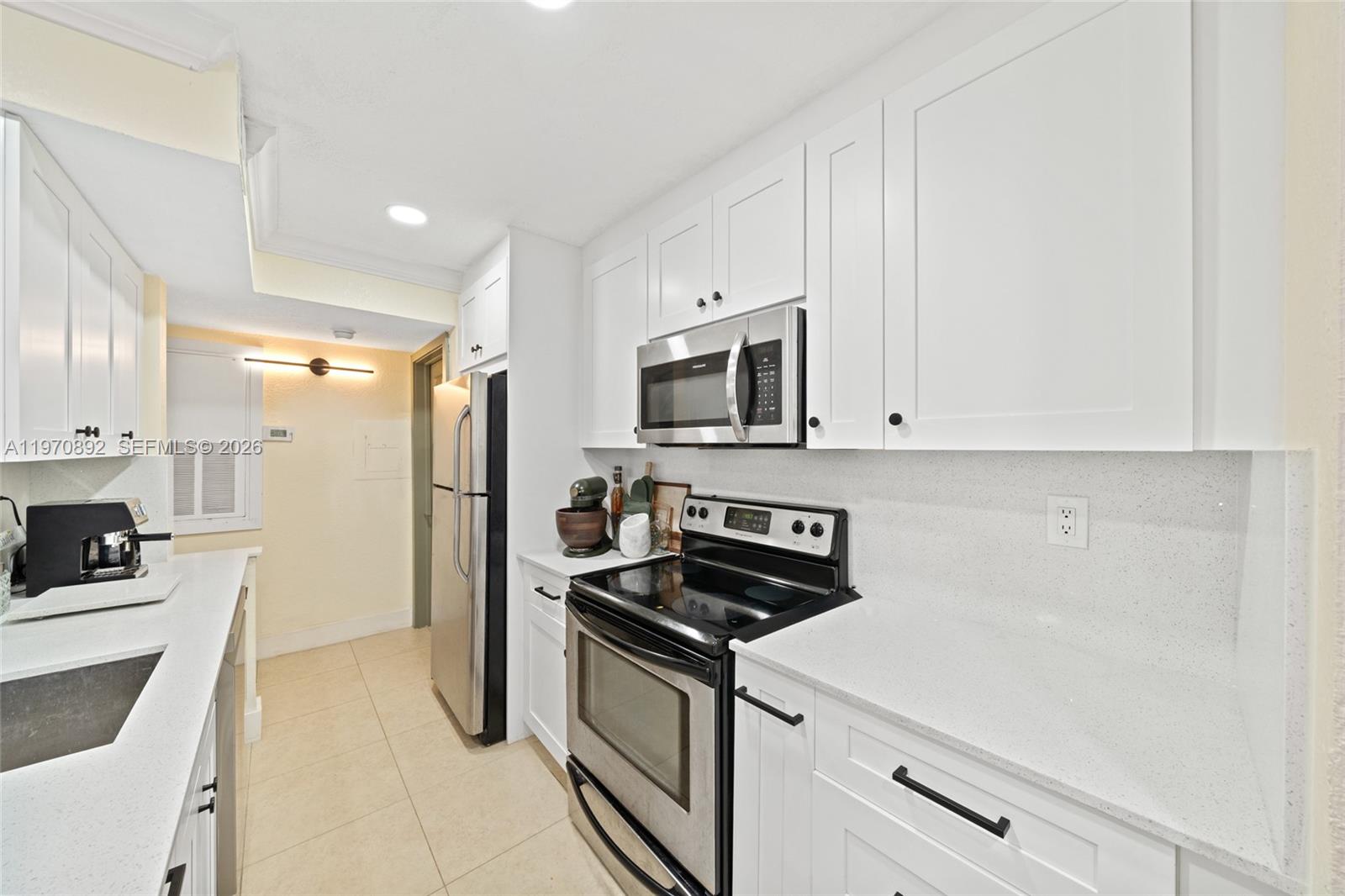15599 Southwest 106th Lane, Unit 1209 Miami, FL 33196 - Photo 2 of 24 a kitchen with white cabinets and stainless steel appliances