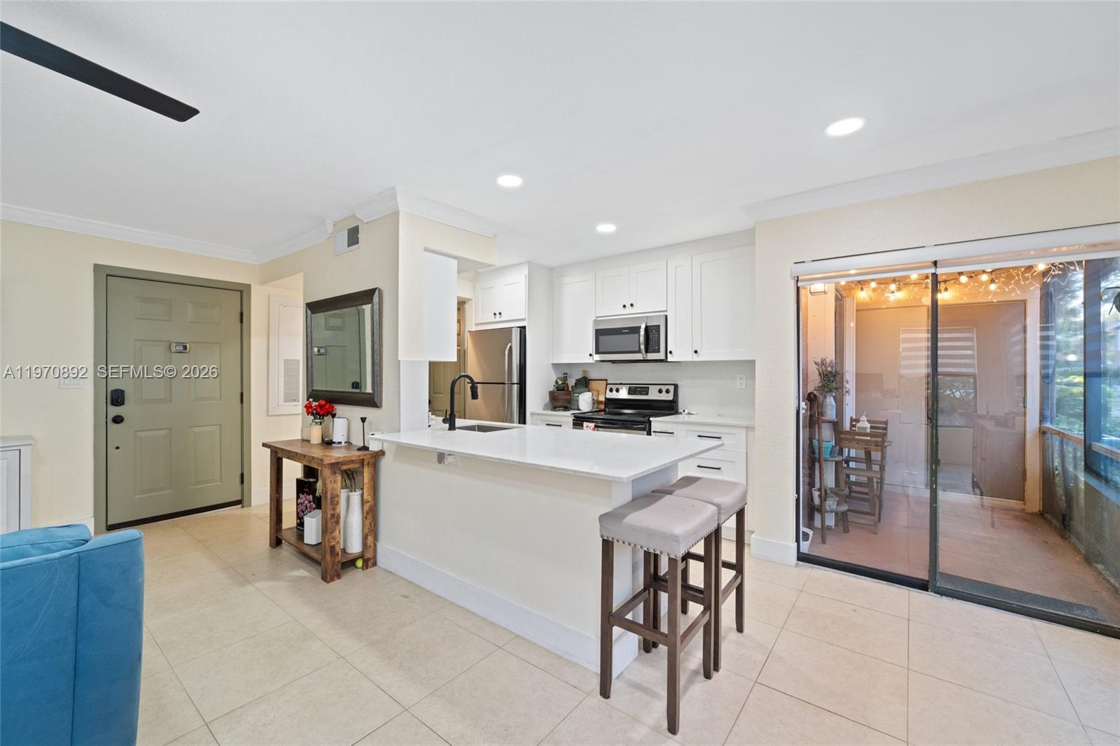15599 Southwest 106th Lane, Unit 1209 Miami, FL 33196 - Photo 3 of 24 a kitchen with stainless steel appliances a refrigerator a stove a sink a dining table and chairs