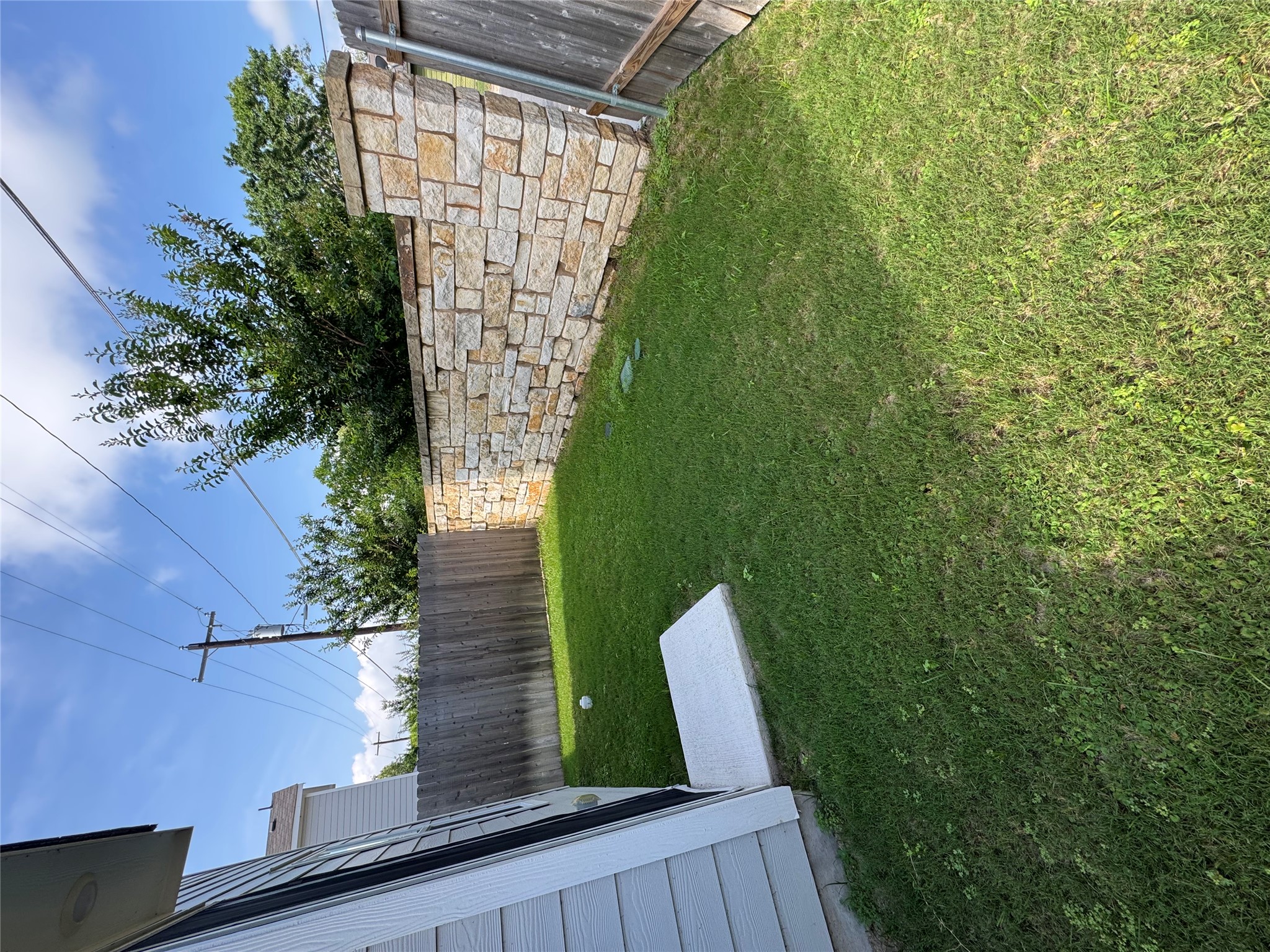 63 Trinity Circle Lockhart, TX 78644 - Photo 14 of 16 A fully fenced backyard offers a private outdoor space with a striking stone accent wall.