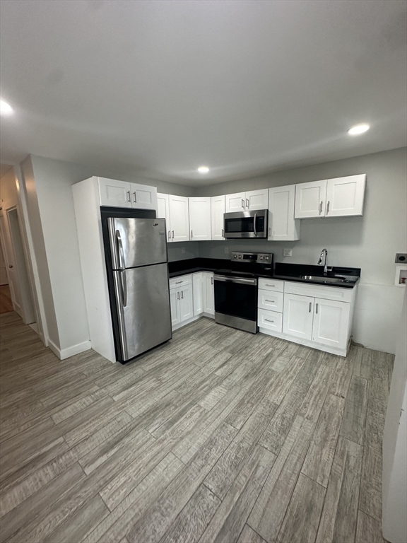 a kitchen with granite countertop a refrigerator stove top oven and sink
