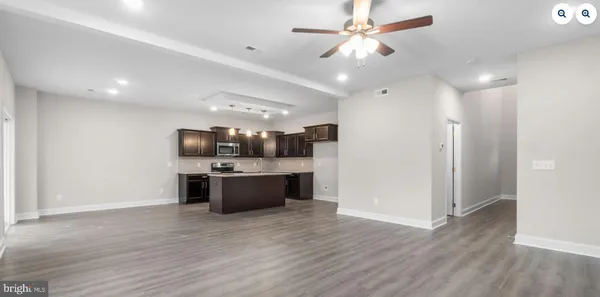 a large kitchen with a large counter top a sink and stainless steel appliances