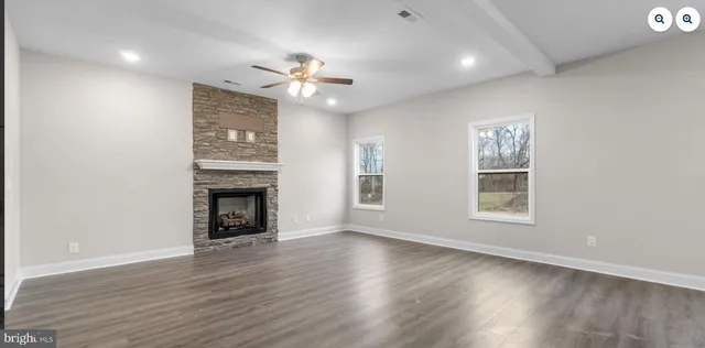an empty room with wooden floor fireplace and windows