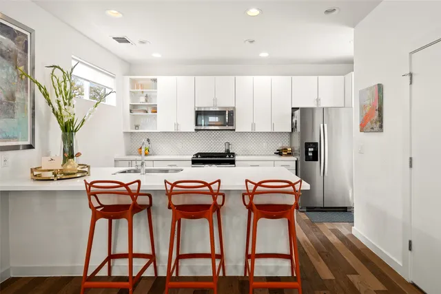 a kitchen with stainless steel appliances a stove a refrigerator a white table and chairs