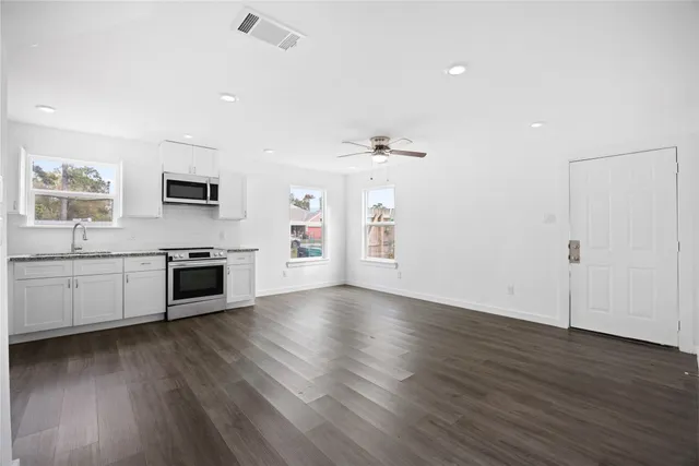 a view of a kitchen with a sink stove cabinets and empty room