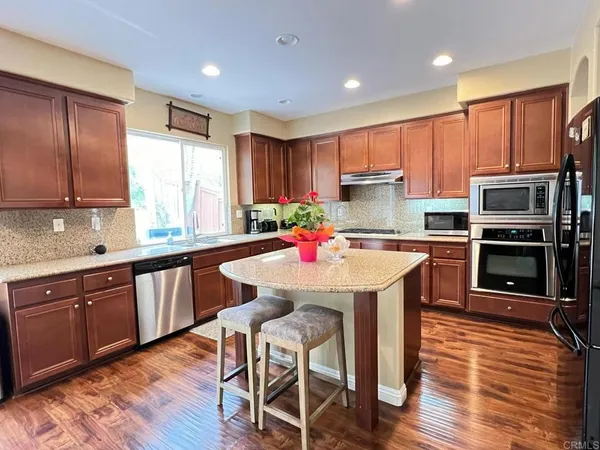 a kitchen with kitchen island granite countertop wooden floors and stainless steel appliances