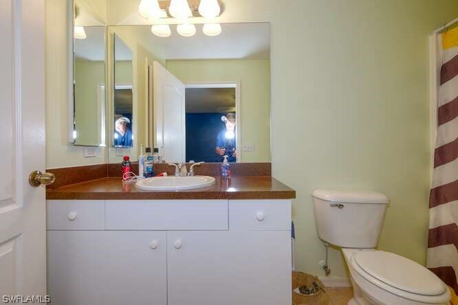 2927 4th Street Southwest Lehigh Acres, FL 33976 - Photo 18 of 19 a bathroom with a sink a toilet a mirror and vanity