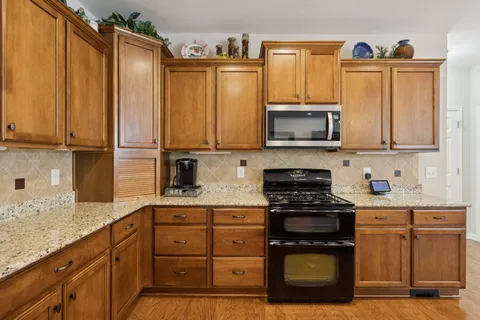 a kitchen with granite countertop a stove top oven microwave and cabinets