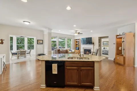 a kitchen with stainless steel appliances granite countertop a sink dishwasher stove and refrigerator with wooden floor