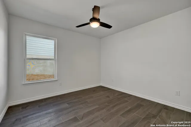a big room with wooden floor a chandelier fan and windows