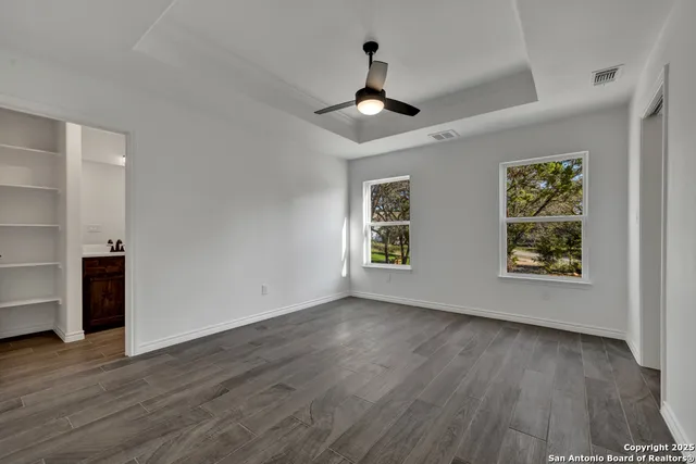 a view of an empty room with a window and wooden floor
