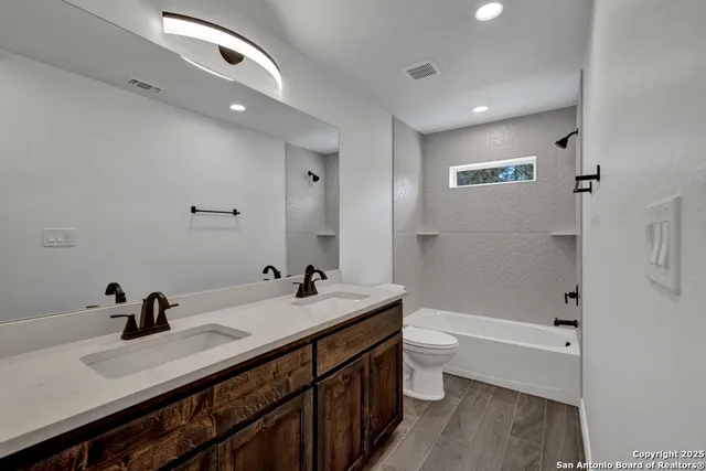 a bathroom with a double vanity sink toilet and shower