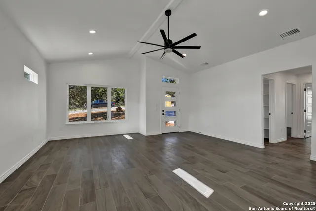 a view of empty room with wooden floor and fan