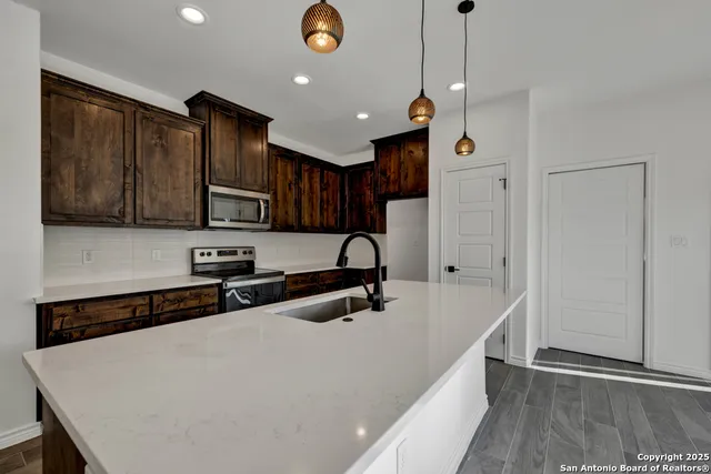 a kitchen with stainless steel appliances a sink a stove a refrigerator cabinets and wooden floor