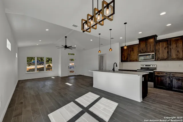 a large kitchen with cabinets wooden floor and stainless steel appliances
