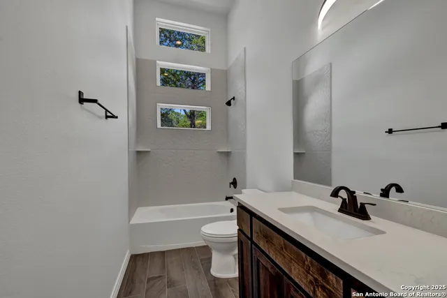 a bathroom with a granite countertop sink a toilet and a bathtub