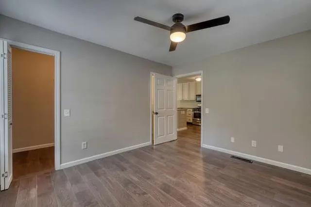 an empty room with wooden floor and a ceiling fan