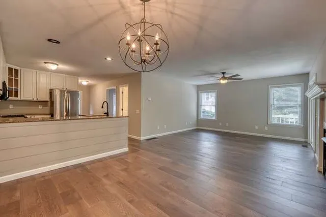 a view of a room with wooden floor and kitchen appliances