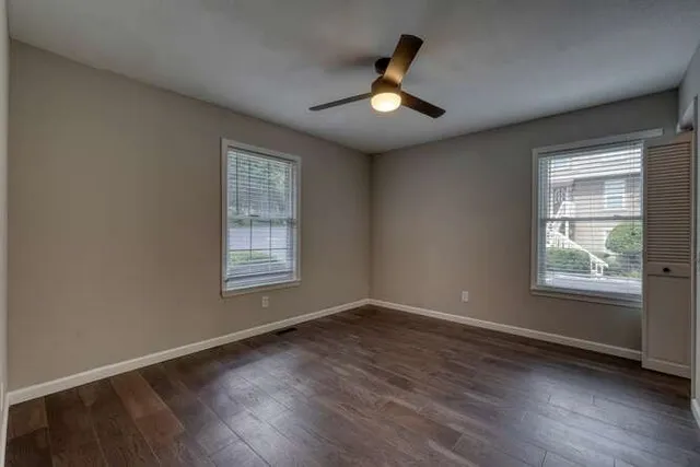 a view of an empty room with wooden floor and a window