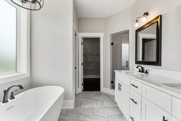 a bathroom with a double vanity sink a mirror and a bathtub