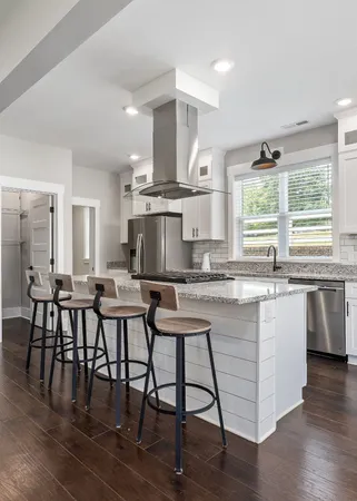 a kitchen with stainless steel appliances granite countertop a stove a sink a microwave a dining table and chairs