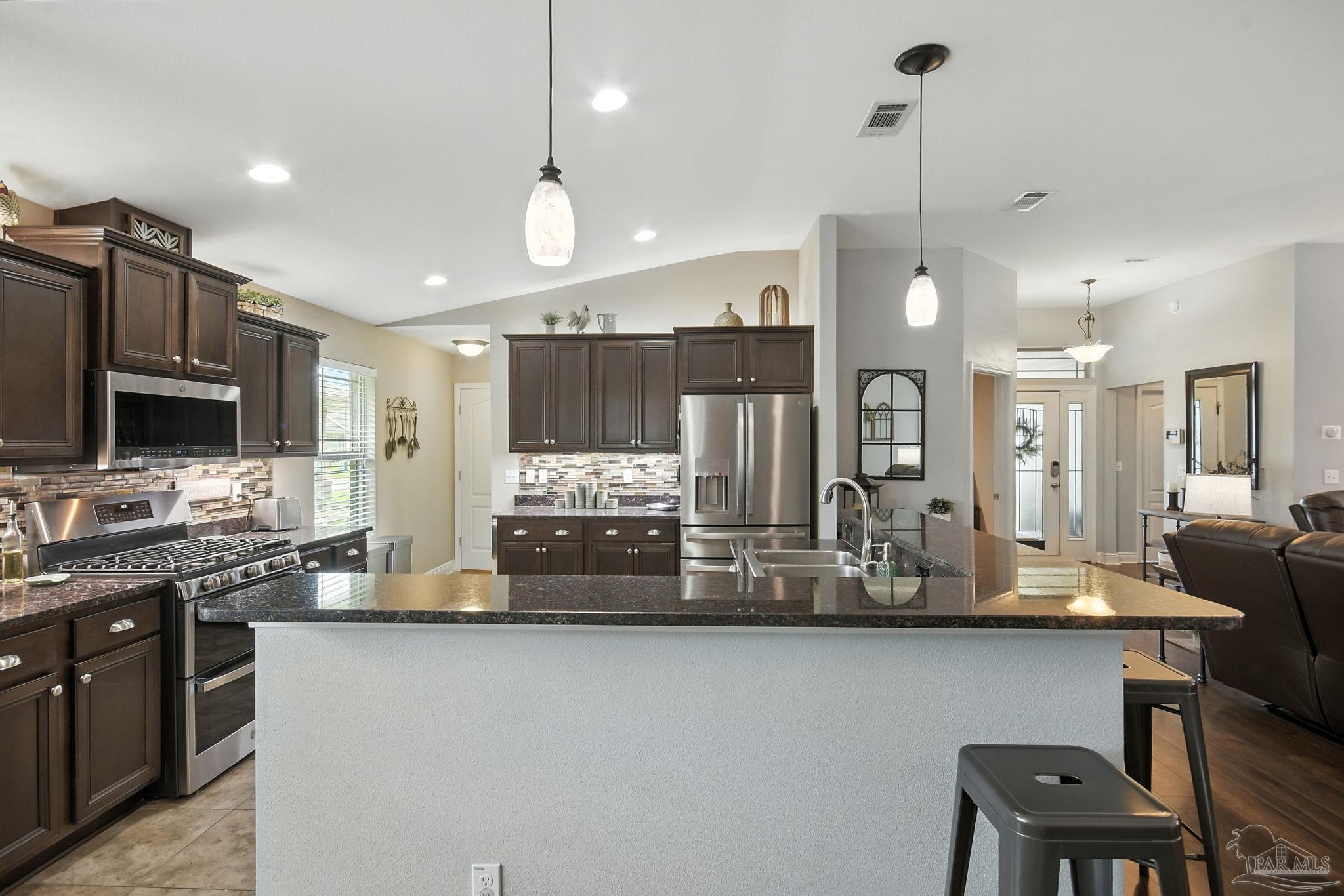 2587 Fiddlers Circle Cantonment, FL 32533 - Photo 24 of 66 a kitchen with stainless steel appliances kitchen island granite countertop a stove a sink and a refrigerator
