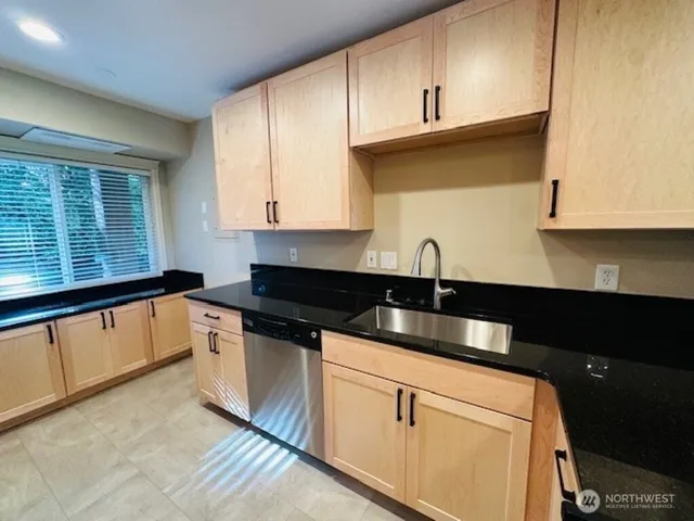 a kitchen with granite countertop a sink and white cabinets