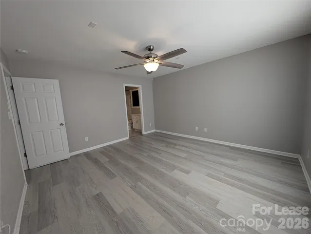 an empty room with wooden floor and fan