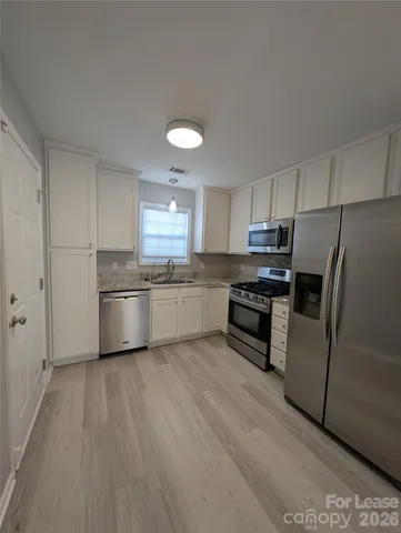 a kitchen with stainless steel appliances a refrigerator sink and white cabinets