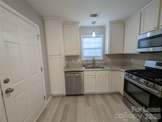 a kitchen with granite countertop a sink stove and cabinets