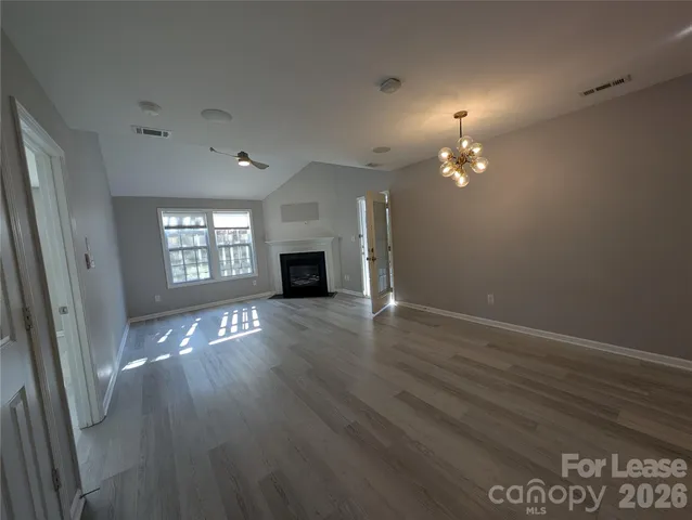 an empty room with wooden floor fireplace and windows