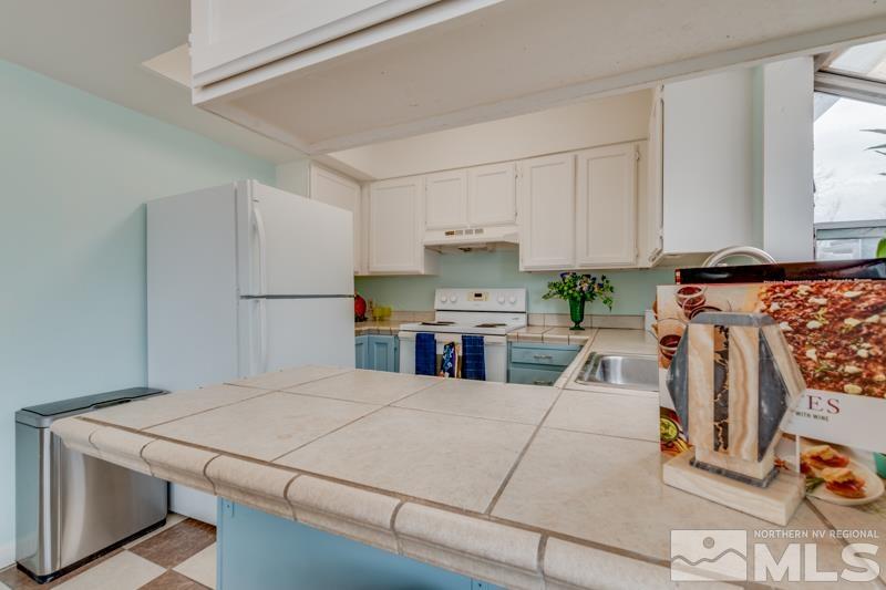 1340 Ralston Street Reno, NV 89503 - Photo 8 of 33 a kitchen with stainless steel appliances kitchen island granite countertop a refrigerator a stove a sink and white cabinets with wooden floor