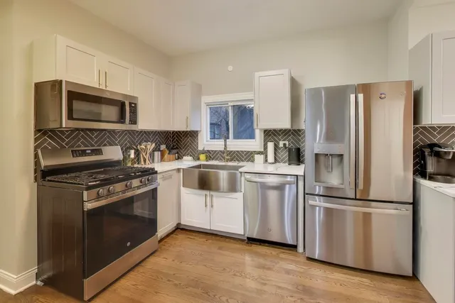 a kitchen with cabinets stainless steel appliances and wooden floor