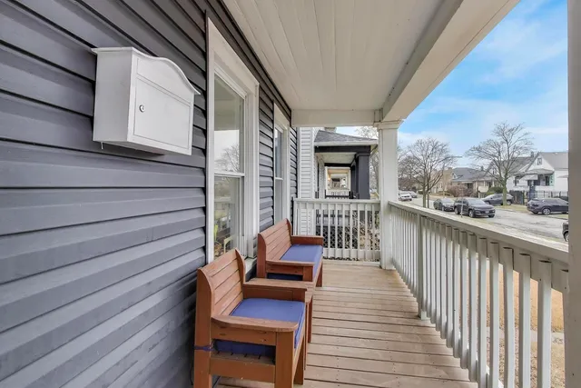 a balcony with wooden floor table and chairs