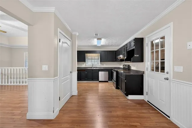 a large kitchen with stainless steel appliances kitchen island granite countertop a stove a refrigerator a sink dishwasher and a oven with wooden floor