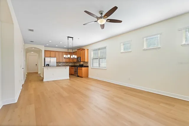 a view of a big room with wooden floor and a kitchen