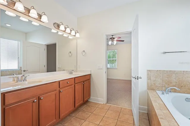a spacious bathroom with a double vanity sink a large mirror and a bathtub