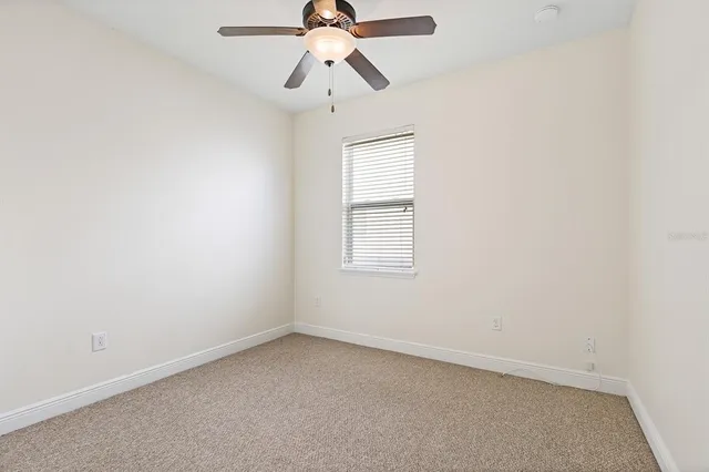 an empty room with a window and a fan