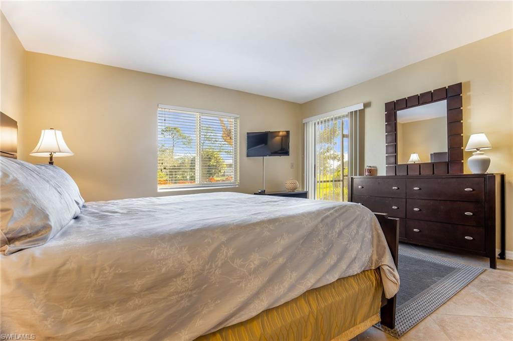 1075 Foxfire Lane, Unit 103 Naples, FL 34104 - Photo 11 of 20 a bedroom with a bed and dresser with mirror