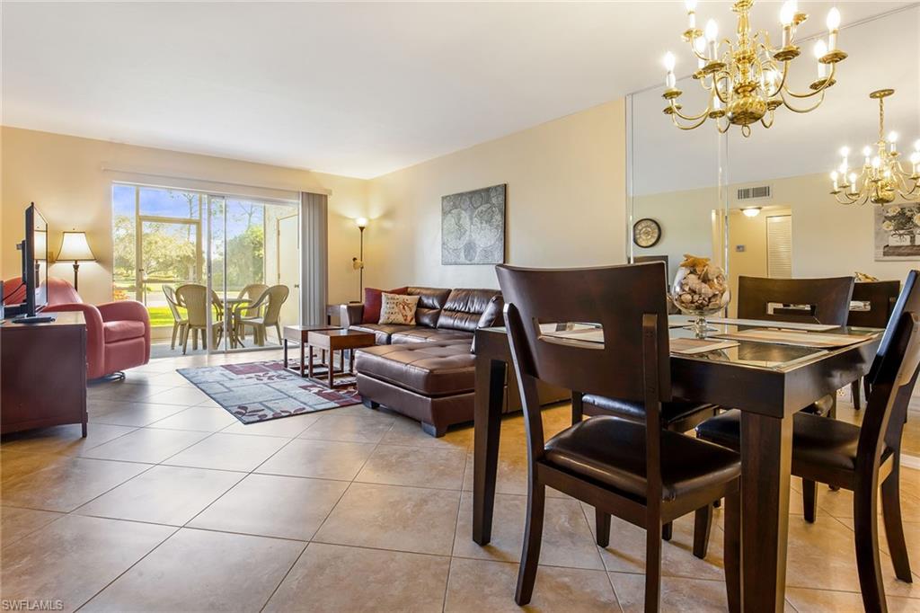 1075 Foxfire Lane, Unit 103 Naples, FL 34104 - Photo 6 of 20 a living room with furniture a chandelier and a dining table