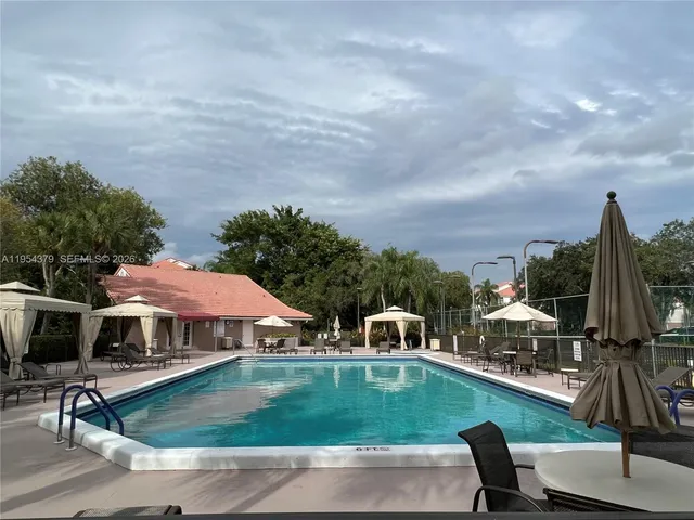 a view of a swimming pool with lawn chairs and a yard